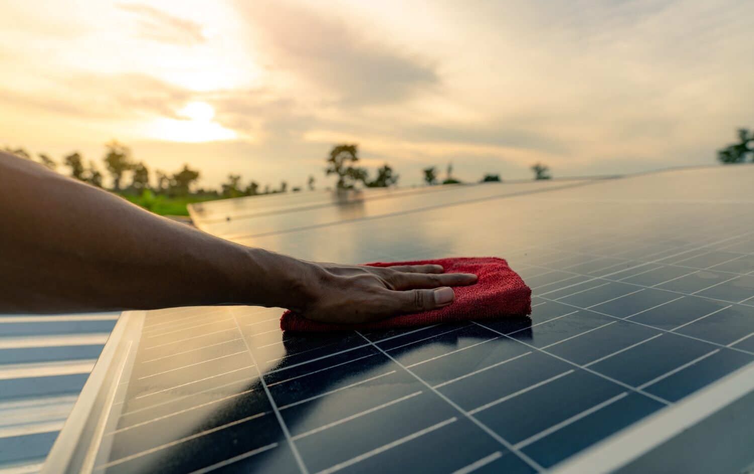 Man cleaning solar panel on roof.