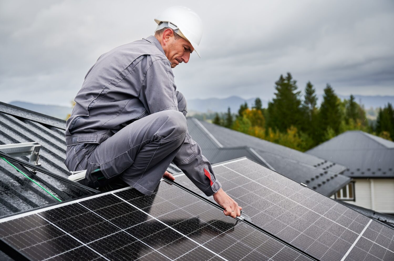 Man technician mounting photovoltaic solar panels on roof of house.